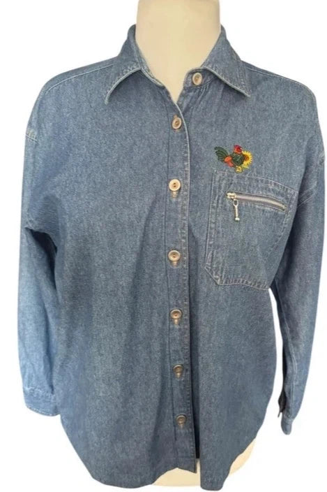Zapięta niebieska koszula jeansowa vintage na manekinie, z aplikacją koguta i kieszonką z suwakiem