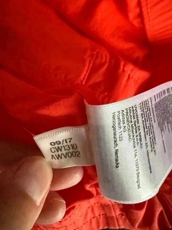 Metka wewnętrzna kurtki TrickandChic Adidas Originals z kodem modelu CW1310 na pomarańczowym materiale ortalionowym
