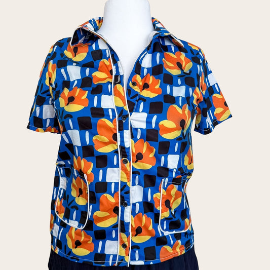 Satynowa bluzka TrickandChic w stylu retro z niebieskim wzorem w kwiaty, krótkim rękawem i białymi lamówkami.