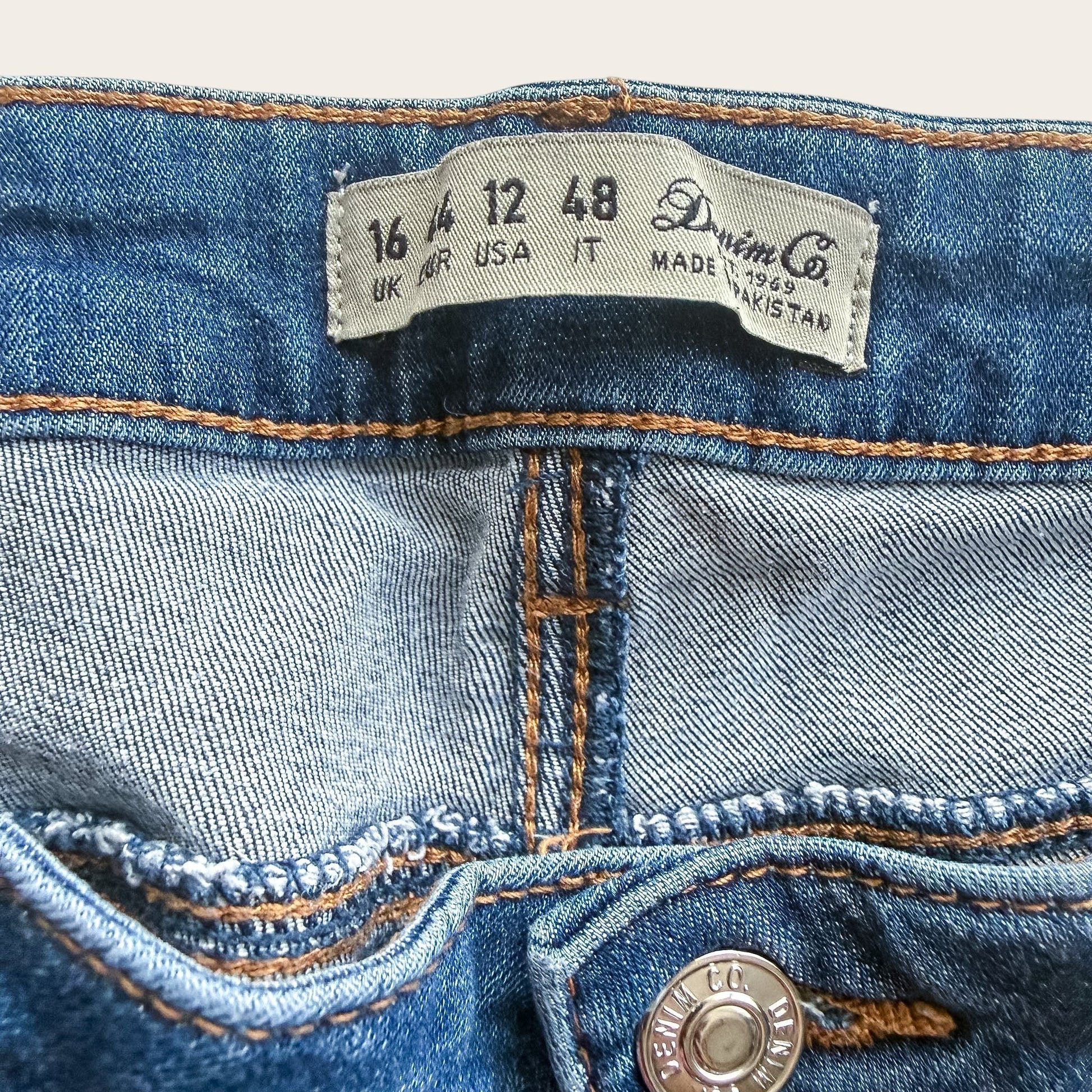 Metka jeansów TrickandChic Denim&Co z oznaczeniem rozmiaru 44 oraz widoczne szwy i guzik z logo marki